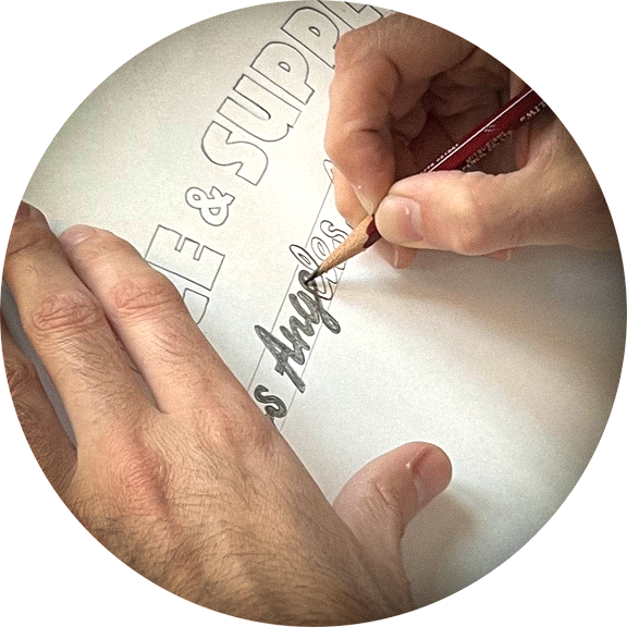 Hand using a pencil to write on a white surface with text.